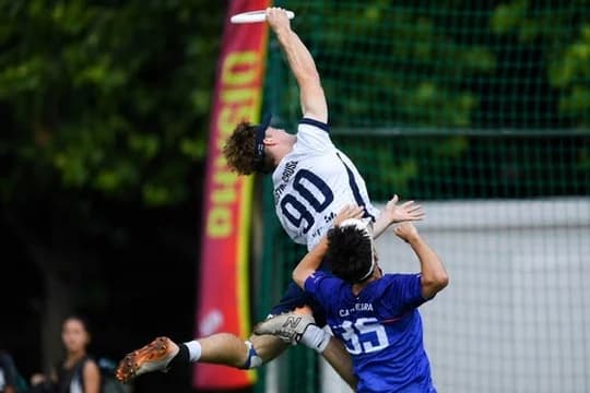Ethan, in a white USA jersey number 90, fully extended in the air to catch a disc over a defender.